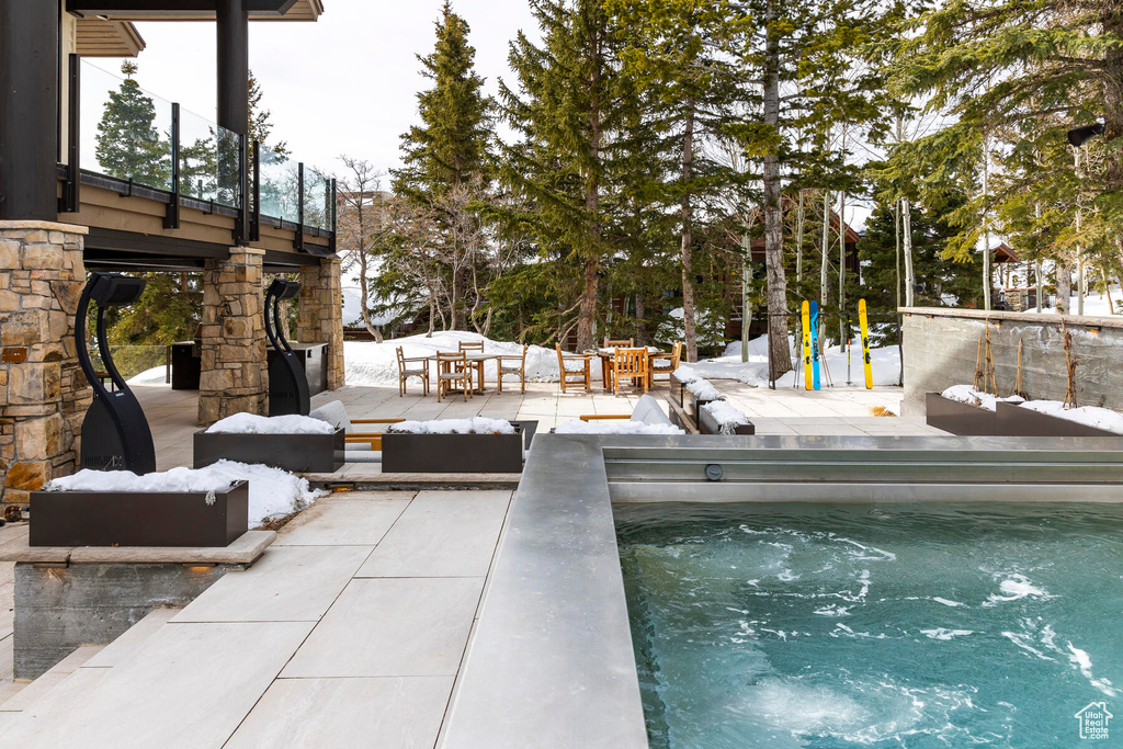 Snow covered pool featuring a patio area and a hot tub