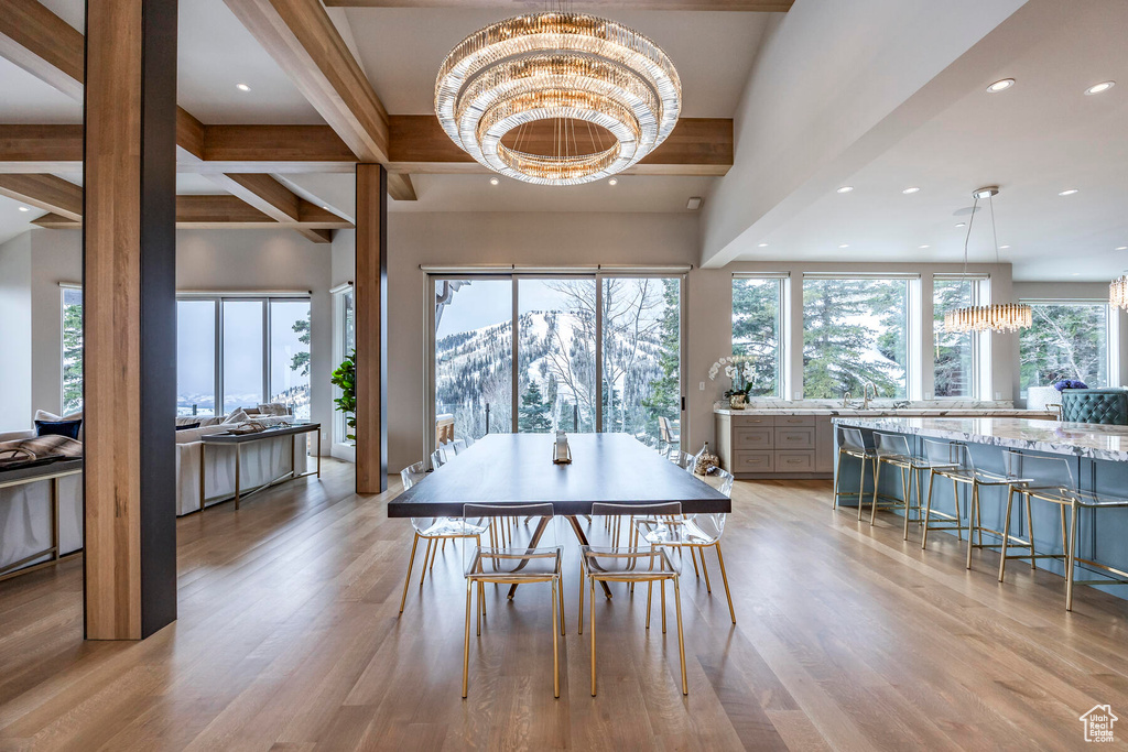 Dining space featuring an inviting chandelier, beam ceiling, and light wood-type flooring