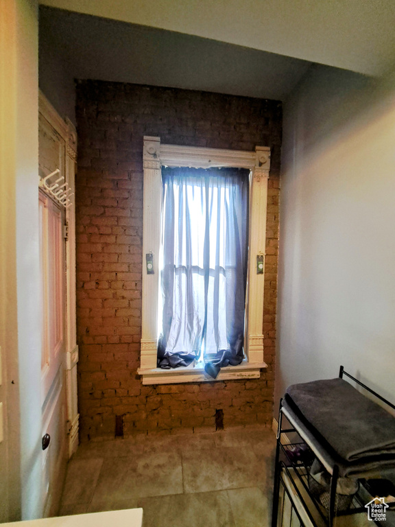 Miscellaneous room featuring brick wall and light tile floors