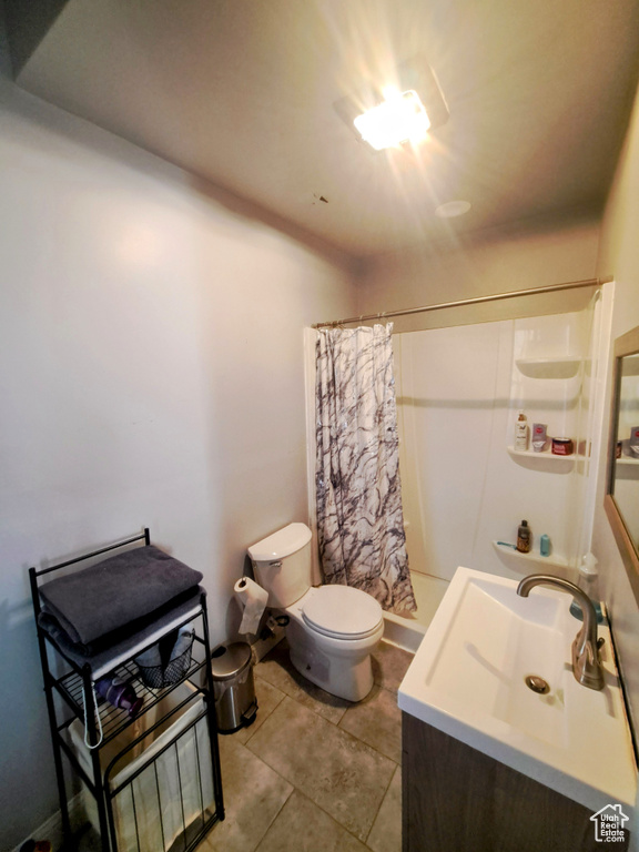 Bathroom with curtained shower, toilet, tile floors, and vanity