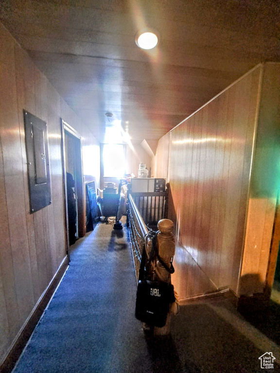 Corridor featuring wood walls and dark carpet