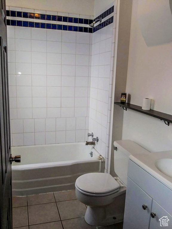 Full bathroom featuring toilet, tile floors, tiled shower / bath combo, and vanity