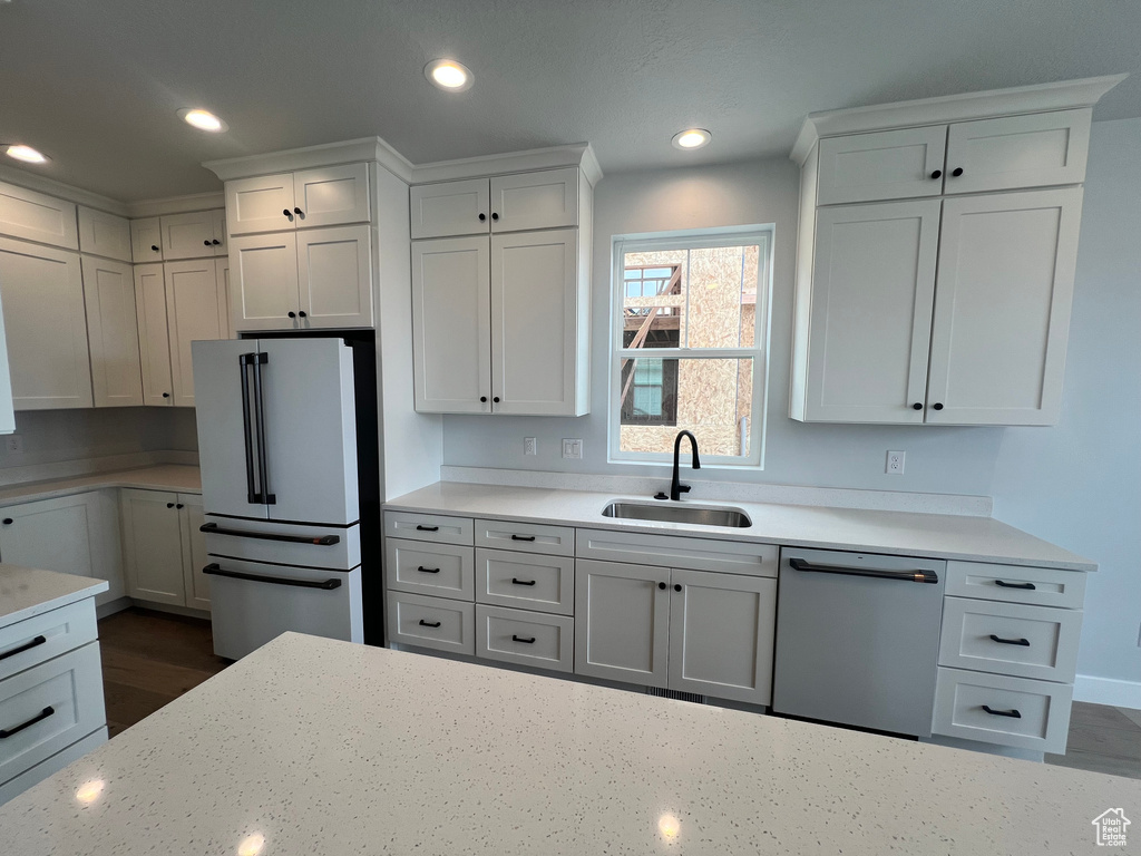 Kitchen with high end white refrigerator, white cabinets, sink, and dishwasher