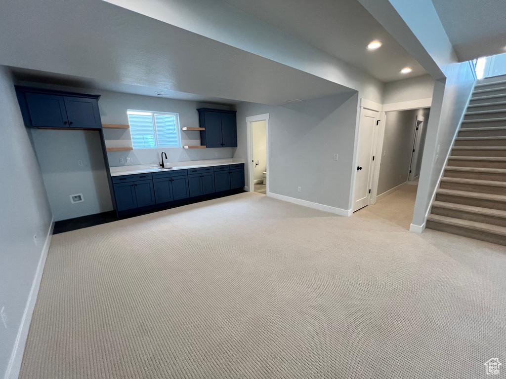 Unfurnished living room featuring light colored carpet and sink