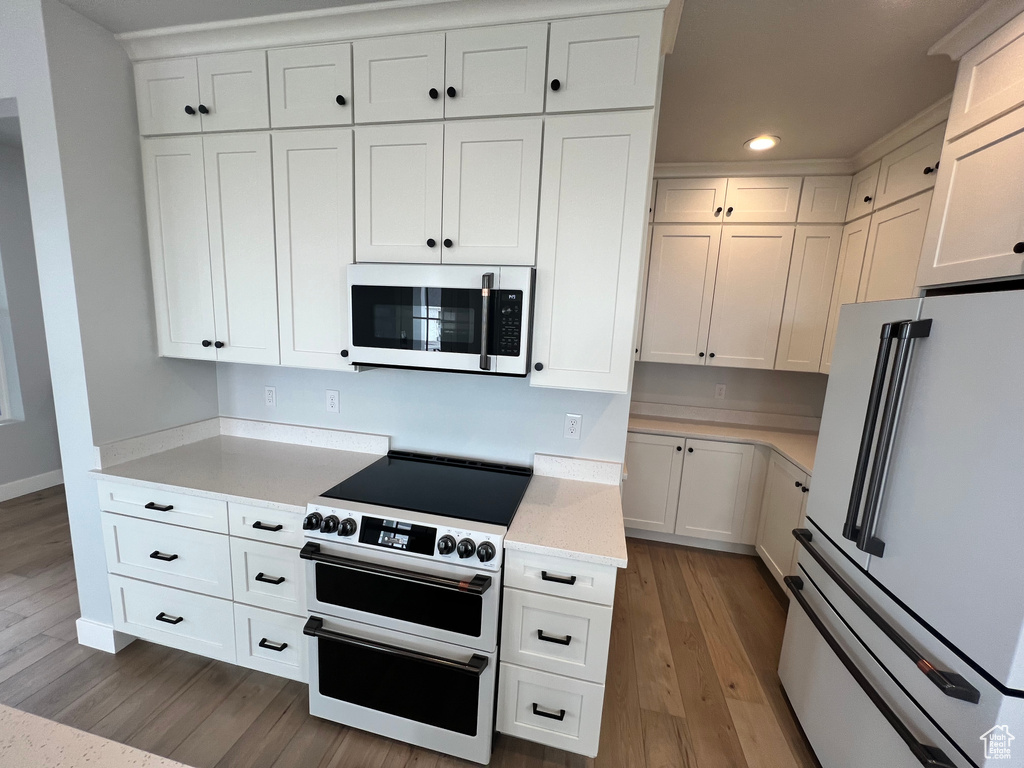 Kitchen with white appliances, white cabinets, and hardwood / wood-style flooring