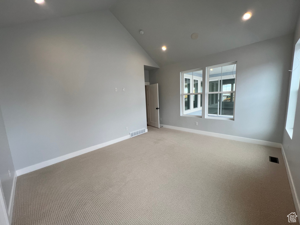 Unfurnished room with high vaulted ceiling and light colored carpet