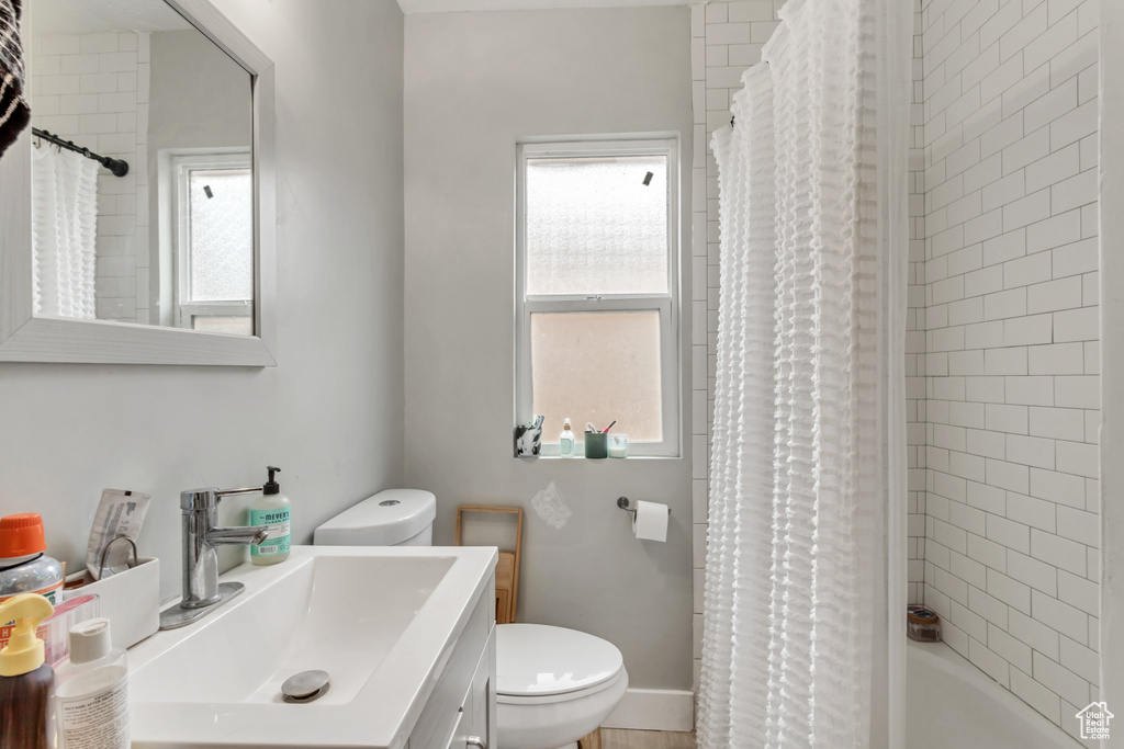 Full bathroom with plenty of natural light, toilet, shower / bathtub combination with curtain, and large vanity