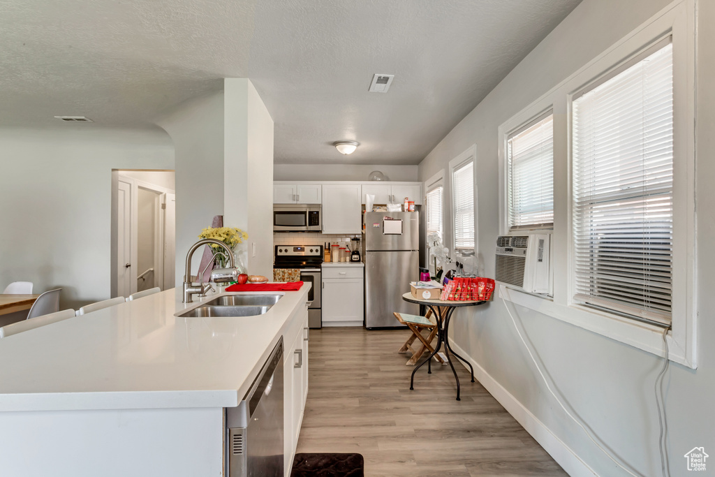 Kitchen featuring white cabinets, light hardwood / wood-style floors, sink, and stainless steel appliances