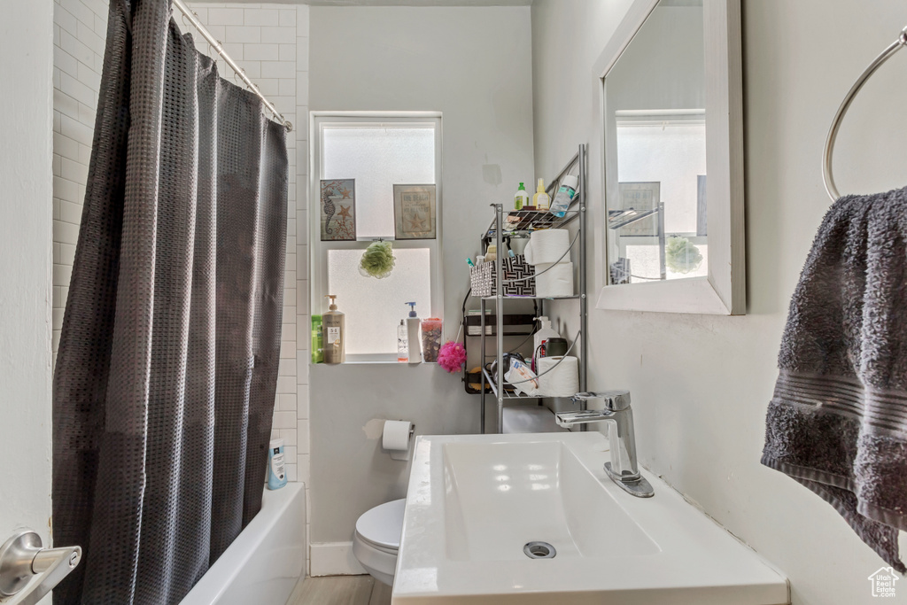 Full bathroom featuring plenty of natural light, shower / bath combination with curtain, toilet, and sink