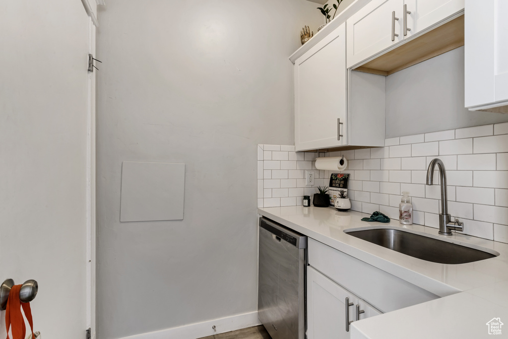Kitchen featuring white cabinetry, tasteful backsplash, dishwasher, and sink