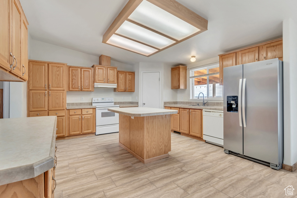 Kitchen with white appliances, a center island, sink, and light tile floors