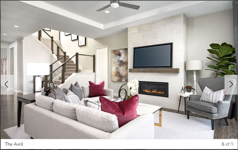 Living room with a raised ceiling, hardwood / wood-style floors, ceiling fan, and a tiled fireplace