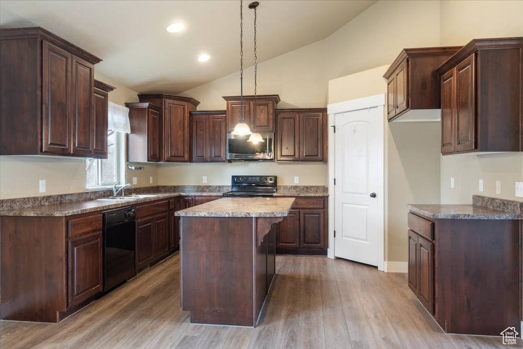 Kitchen with light hardwood / wood-style floors, a kitchen island, dark brown cabinets, black appliances, and pendant lighting