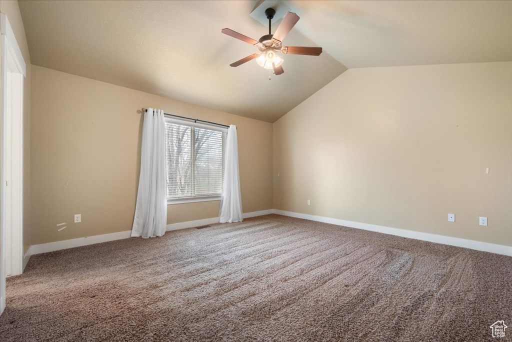 Carpeted empty room with ceiling fan and vaulted ceiling