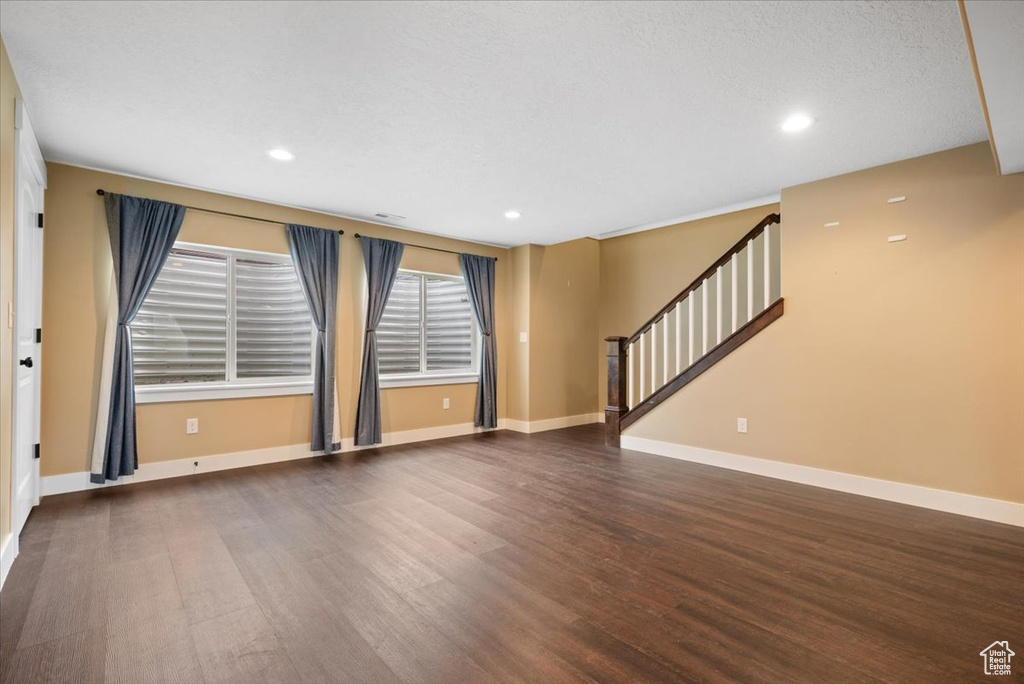 Empty room with dark hardwood / wood-style flooring and a textured ceiling