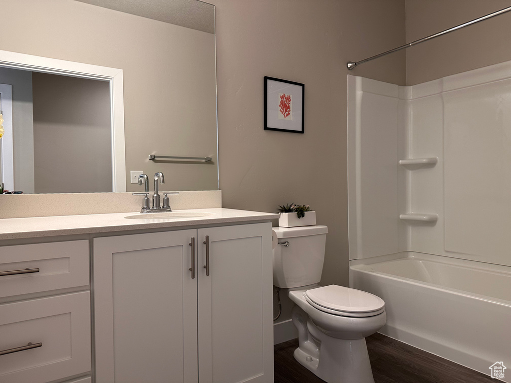 Full bathroom featuring vanity, hardwood / wood-style floors,  shower combination, and toilet