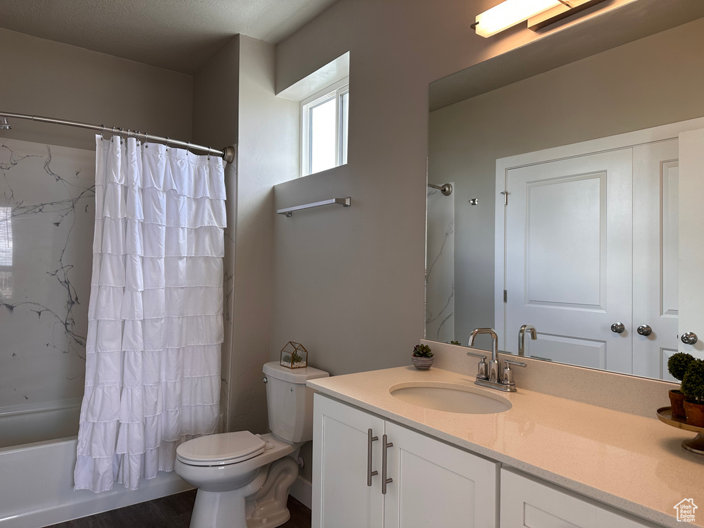 Full bathroom with toilet, vanity, and shower / bath combo with shower curtain