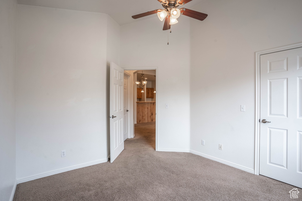 Interior space with light carpet, ceiling fan, and high vaulted ceiling