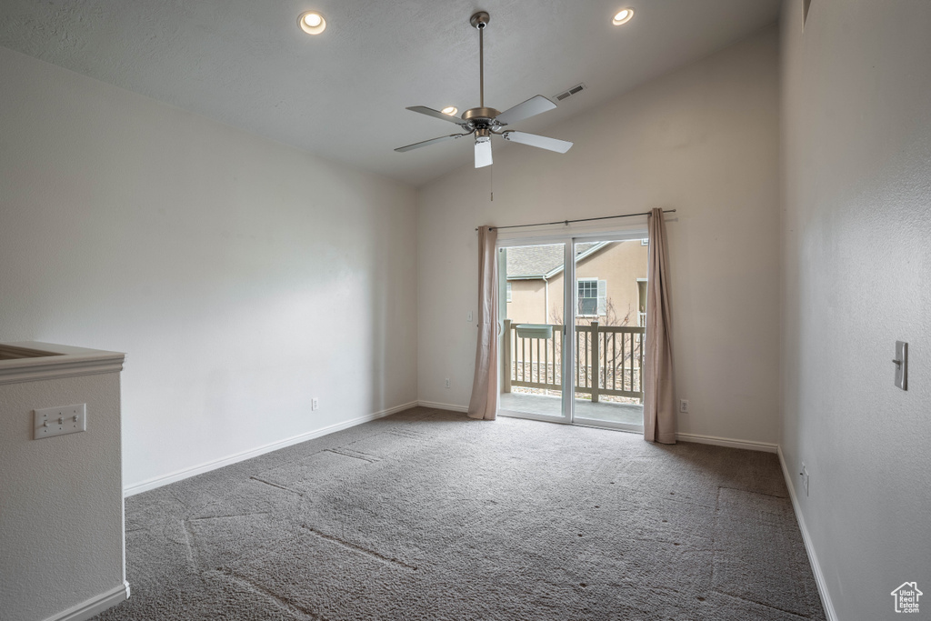 Empty room with dark colored carpet, ceiling fan, and high vaulted ceiling