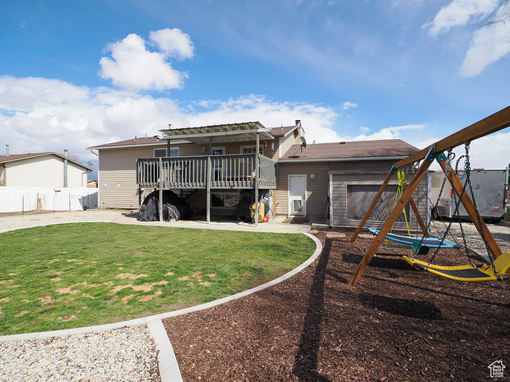 Back of property with a playground, a deck, and a yard
