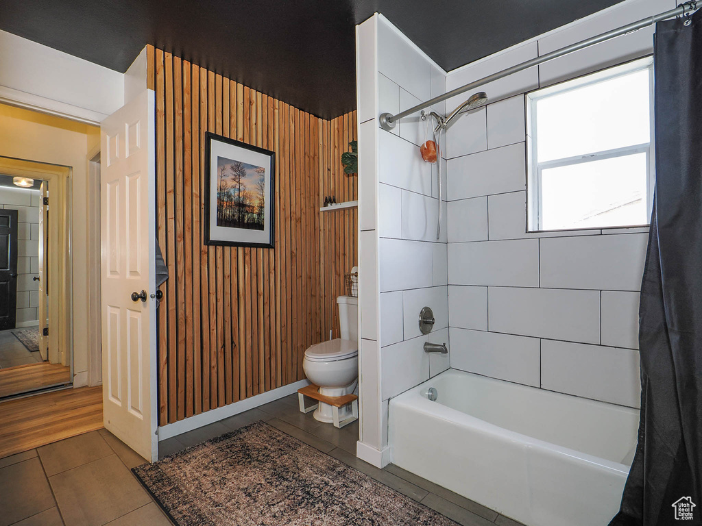 Bathroom with tile floors, shower / bath combo, and toilet