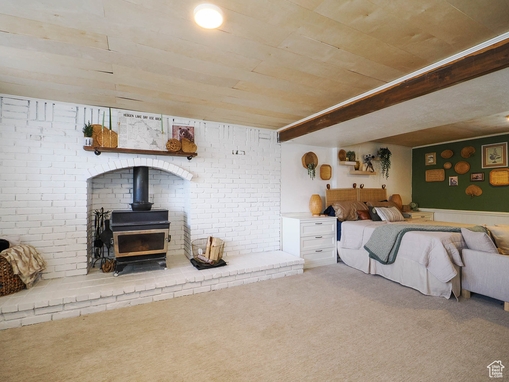 Living room featuring brick wall, a wood stove, and light carpet