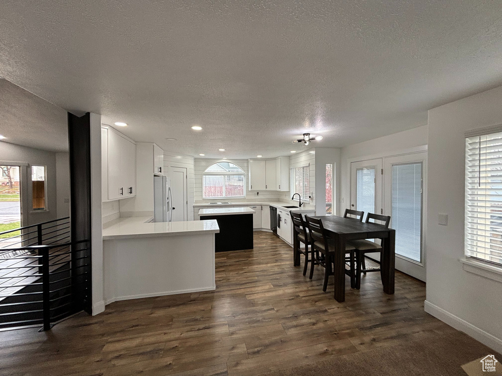 Kitchen featuring plenty of natural light, kitchen peninsula, dark hardwood / wood-style floors, and white cabinetry