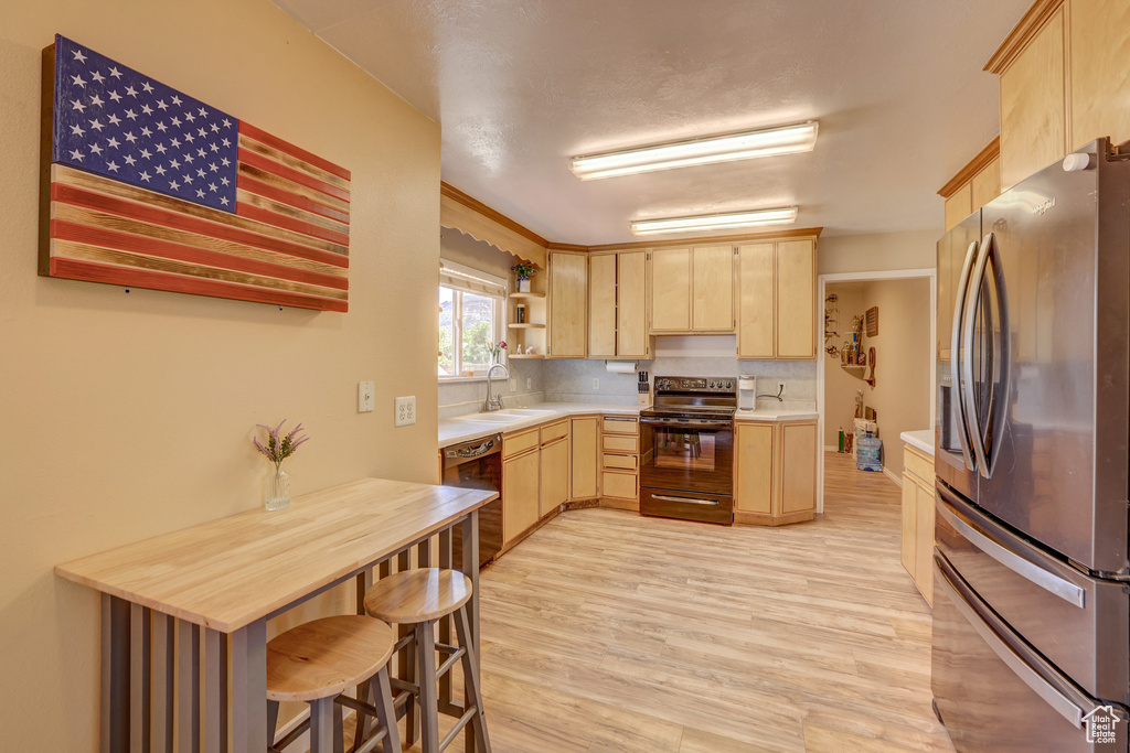 Kitchen featuring light brown cabinetry, stainless steel fridge, light hardwood / wood-style flooring, electric range oven, and tasteful backsplash