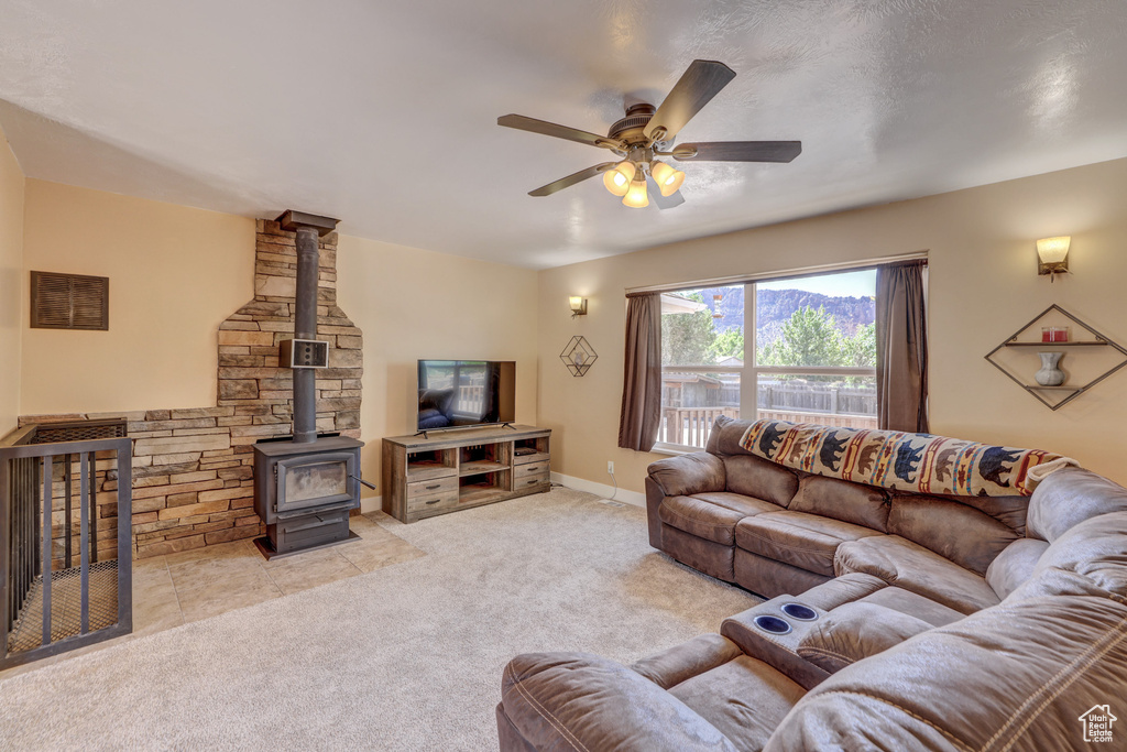Carpeted living room featuring ceiling fan and a wood stove
