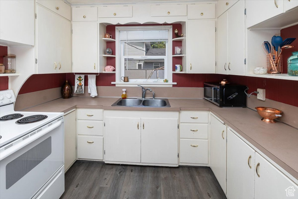 Kitchen featuring dark hardwood / wood-style flooring, white electric range oven, white cabinetry, and sink