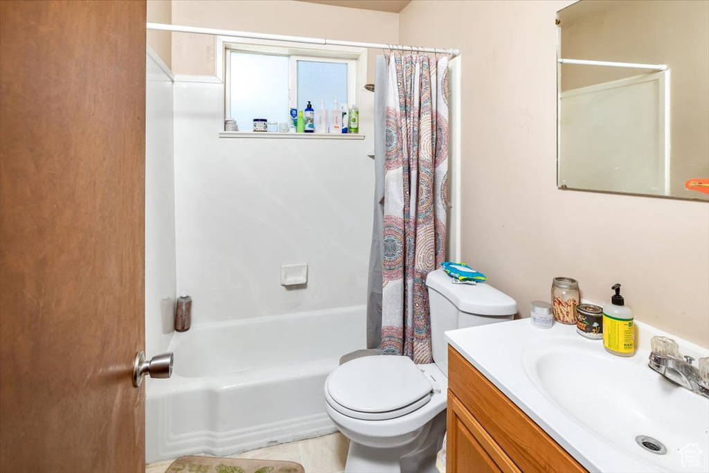 Full bathroom featuring tile floors, toilet, vanity, and shower / bathtub combination with curtain