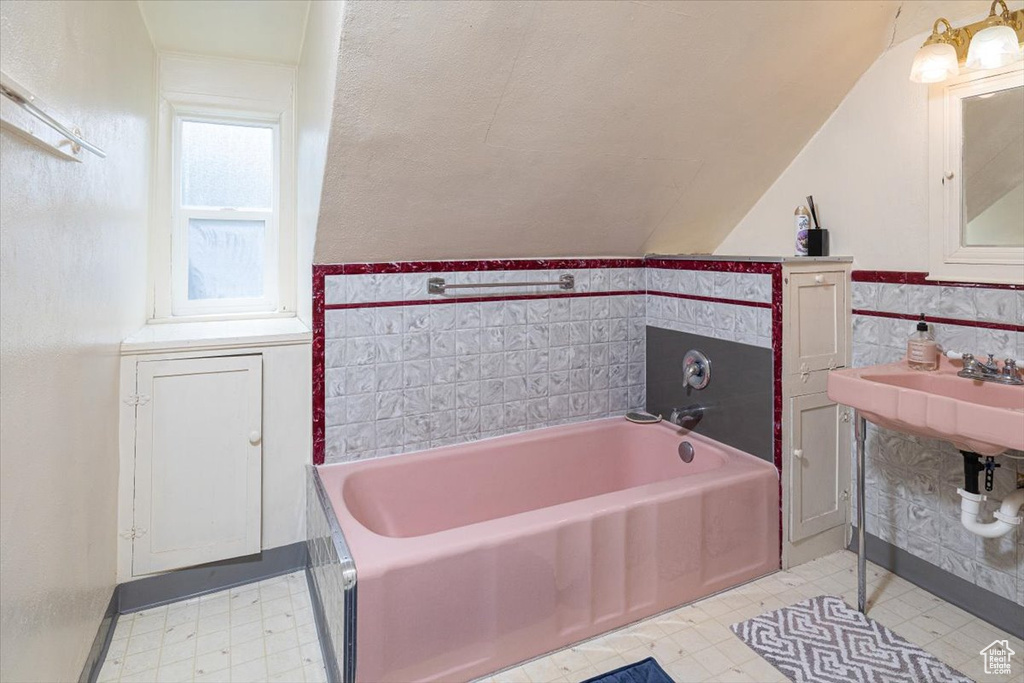Bathroom featuring lofted ceiling, tile flooring, and a bathtub