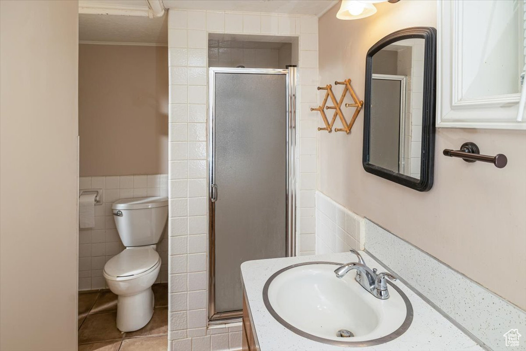 Bathroom featuring toilet, large vanity, crown molding, tile walls, and tile floors