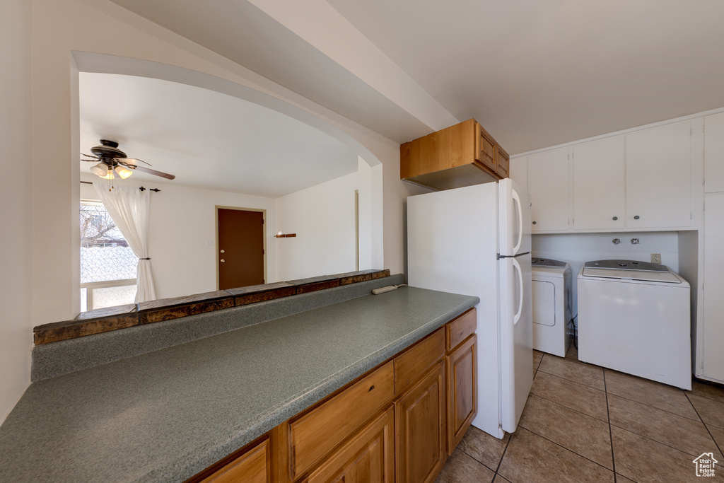 Kitchen featuring light tile floors, white refrigerator, ceiling fan, white cabinets, and independent washer and dryer