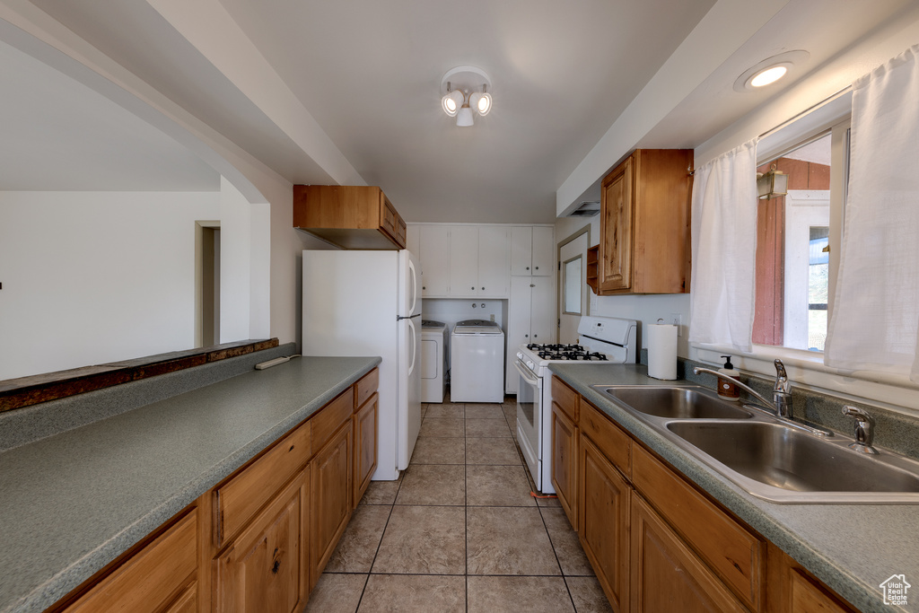 Kitchen with light tile floors, independent washer and dryer, white appliances, and sink
