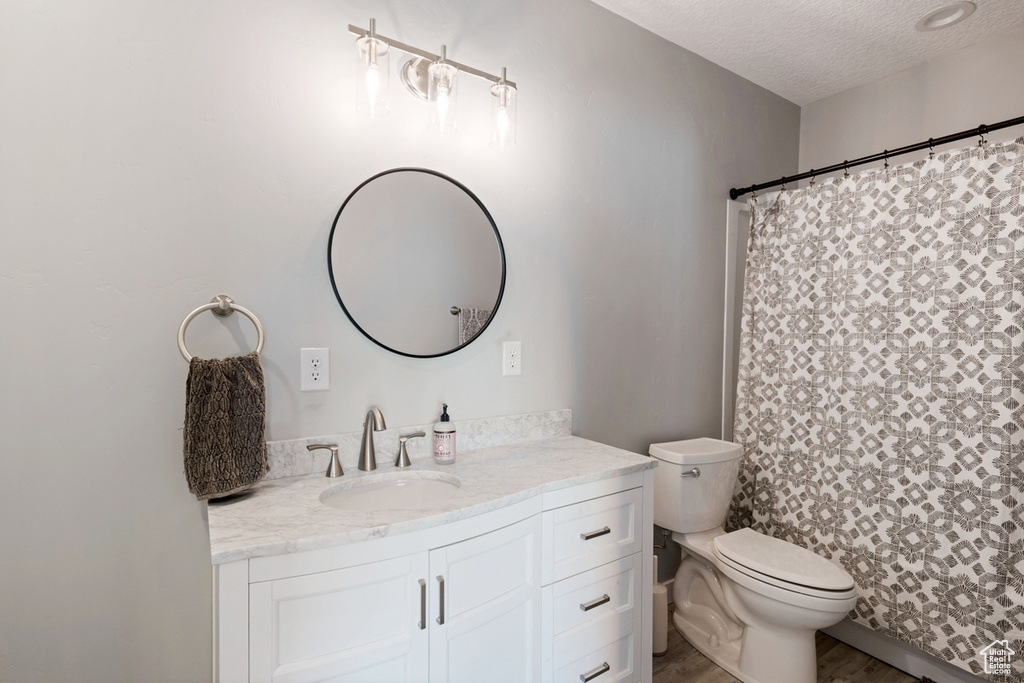 Bathroom with toilet, a textured ceiling, and vanity