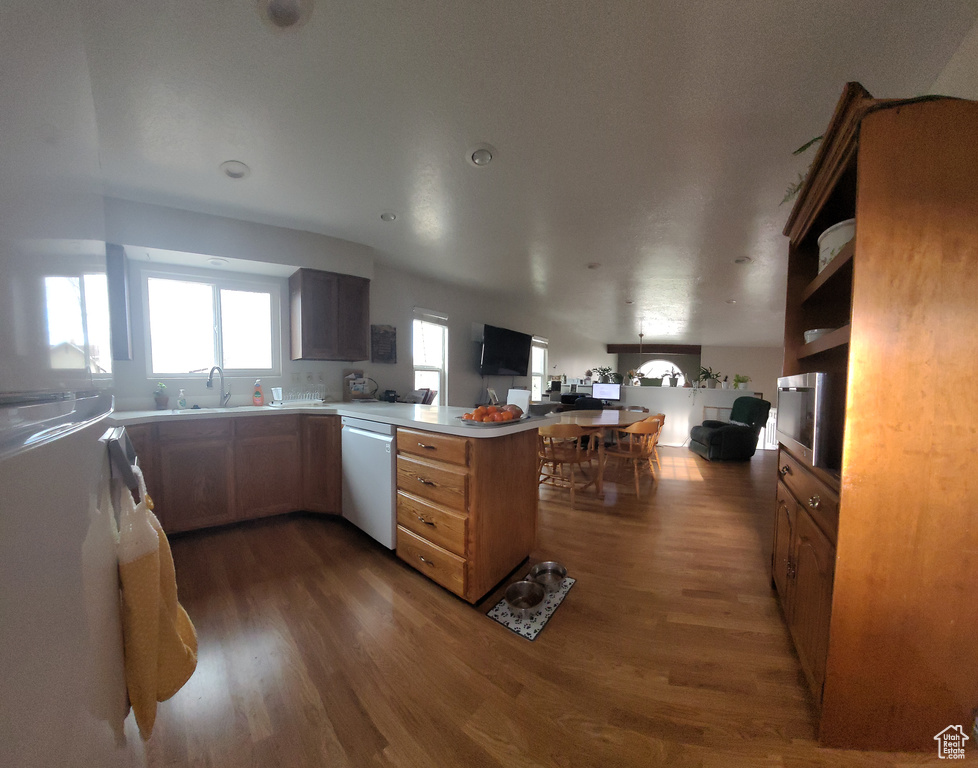 Kitchen with kitchen peninsula, dark hardwood / wood-style flooring, sink, and dishwasher