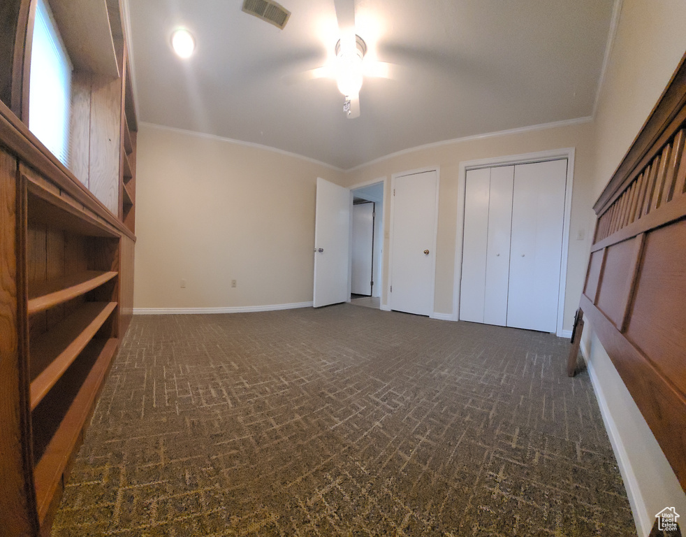Unfurnished bedroom featuring multiple closets and ornamental molding