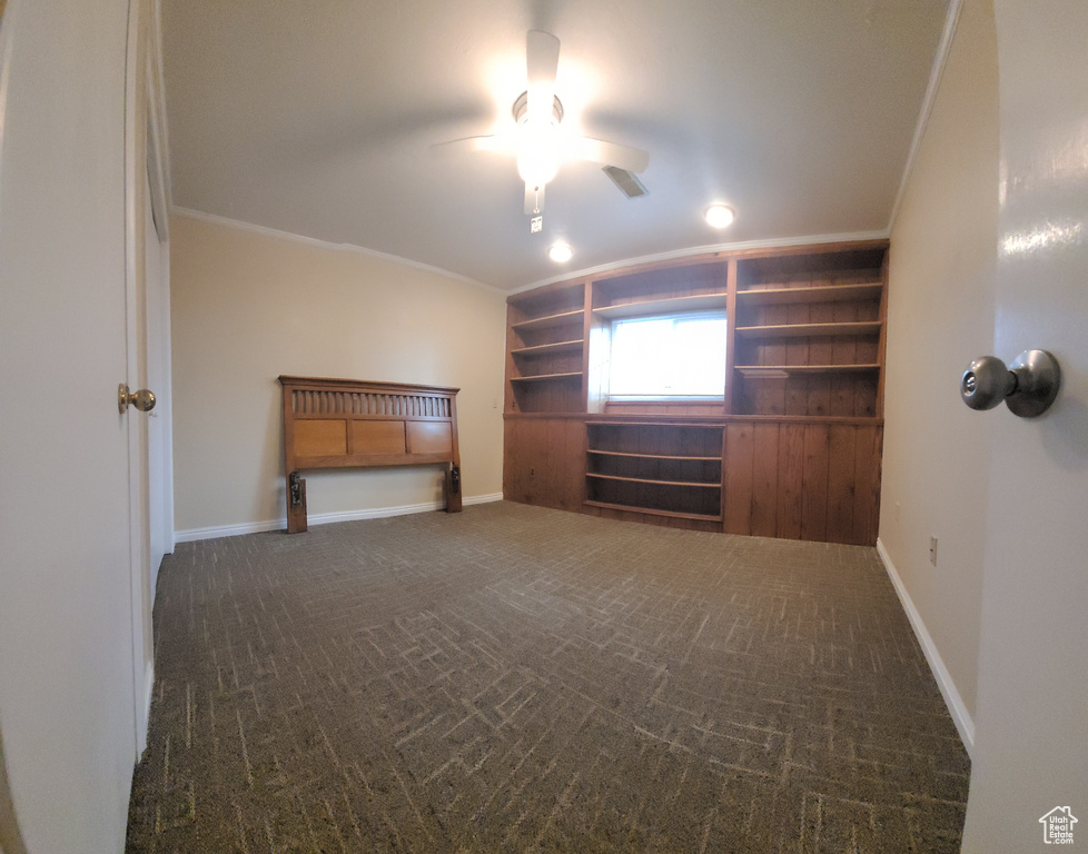 Unfurnished bedroom featuring crown molding, ceiling fan, and dark colored carpet