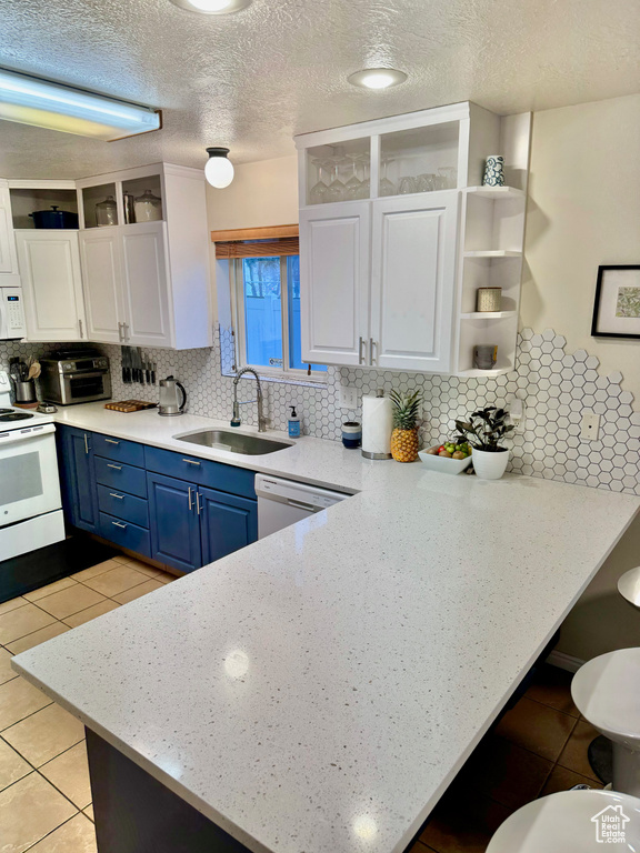 Kitchen featuring white appliances, white cabinetry, tasteful backsplash, and sink
