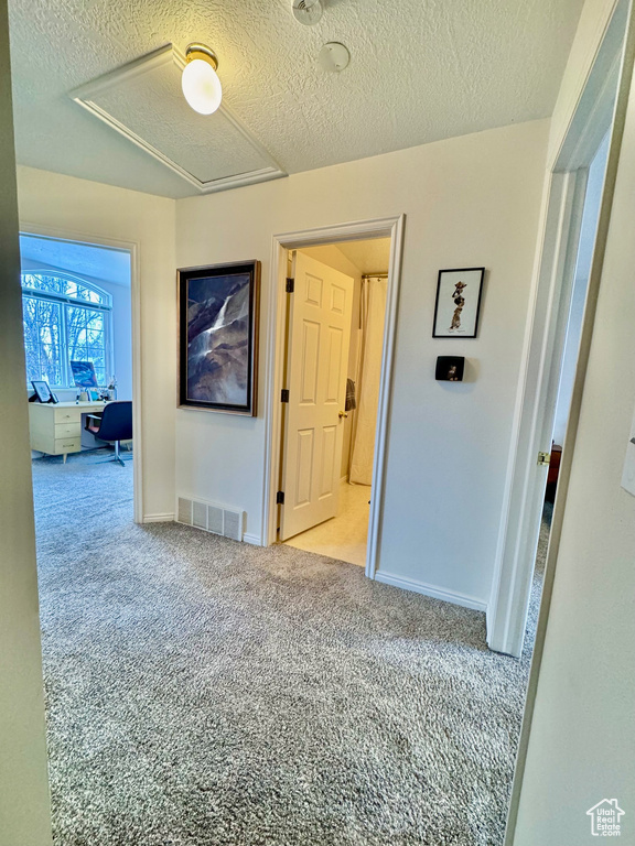 Corridor with a textured ceiling and light colored carpet