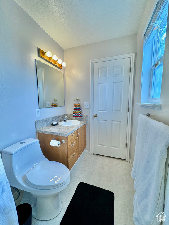 Bathroom featuring tile floors, toilet, a textured ceiling, and vanity