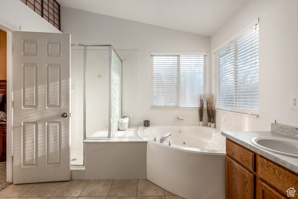 Bathroom with lofted ceiling, tile flooring, separate shower and tub, and vanity