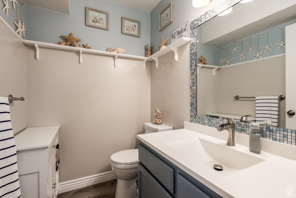 Bathroom featuring tasteful backsplash, toilet, vanity, and hardwood / wood-style floors