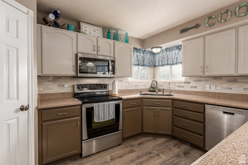 Kitchen featuring stainless steel appliances, tasteful backsplash, gray cabinets, dark hardwood / wood-style floors, and sink