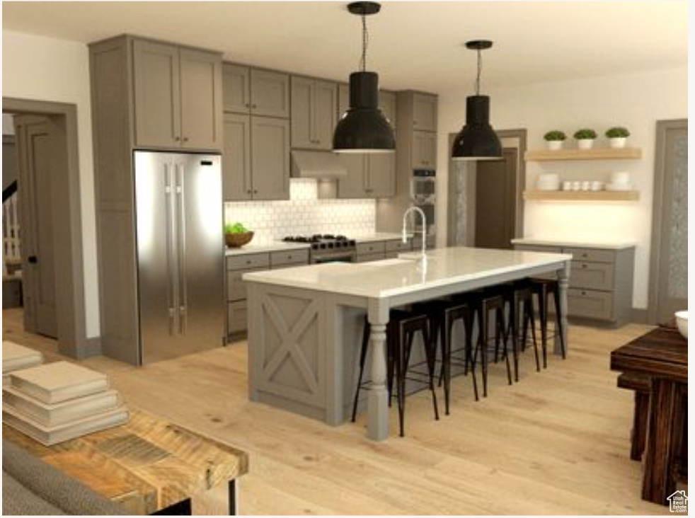 Kitchen with range, gray cabinetry, stainless steel refrigerator, and an island with sink