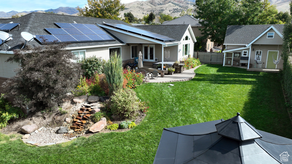 Exterior space with a lawn, solar panels, a mountain view, and a patio area