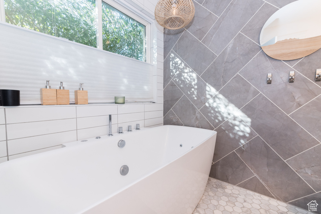 Bathroom featuring tile walls, a bathtub, and tile flooring
