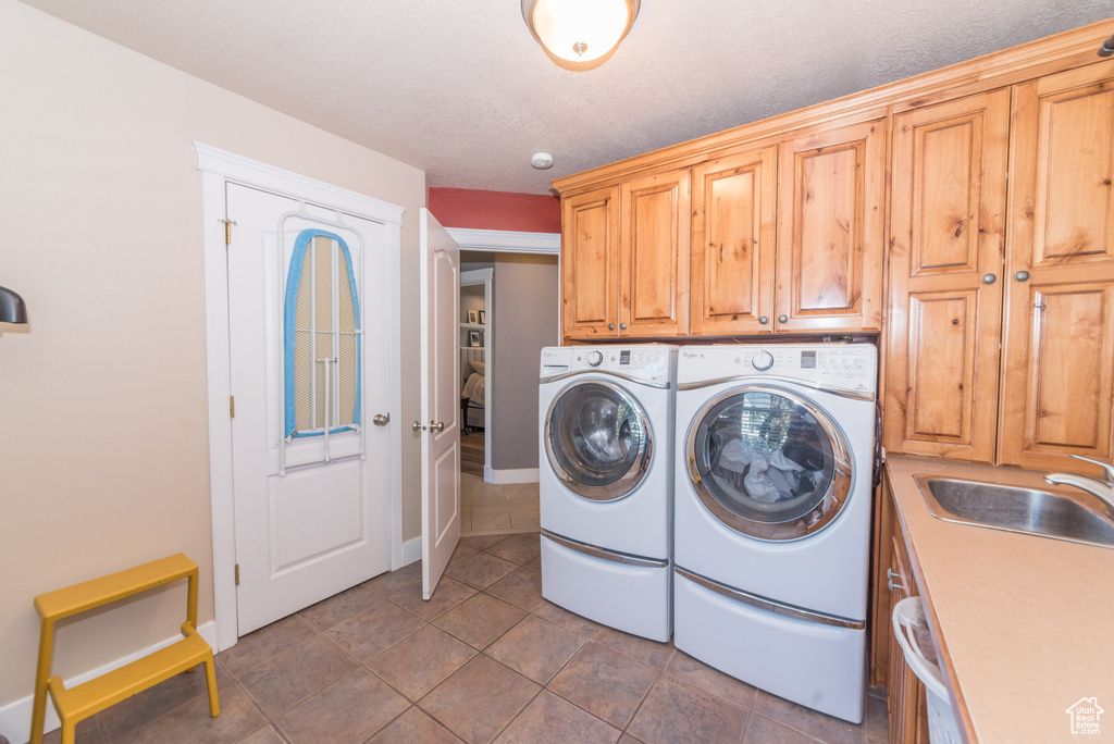 Clothes washing area featuring cabinets, tile flooring, separate washer and dryer, and sink