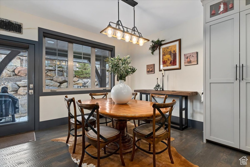 Dining space featuring a chandelier, dark wood-type flooring, and a healthy amount of sunlight